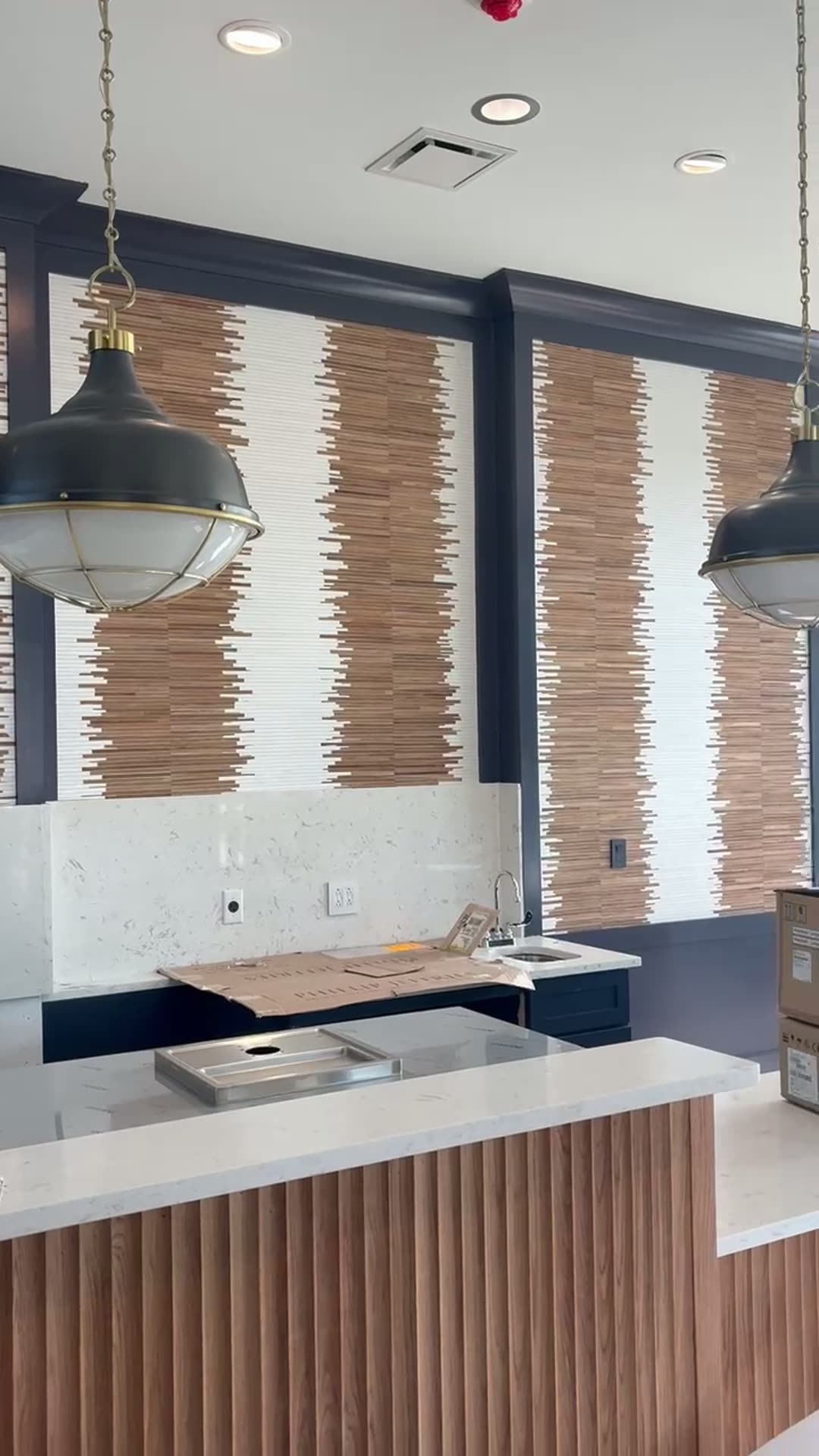 Wood-stripe textural feature walls framed by navy trim with black industrial pendants in a marina café