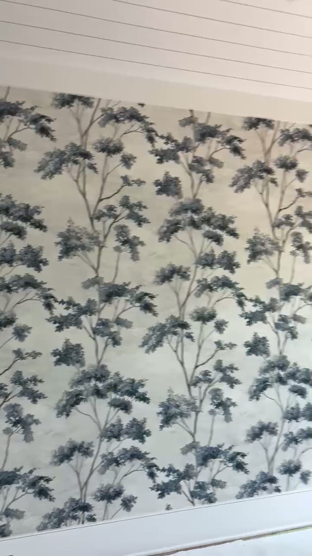 Close-up of the delicate blue branch toile pattern on a plaster-textured ground