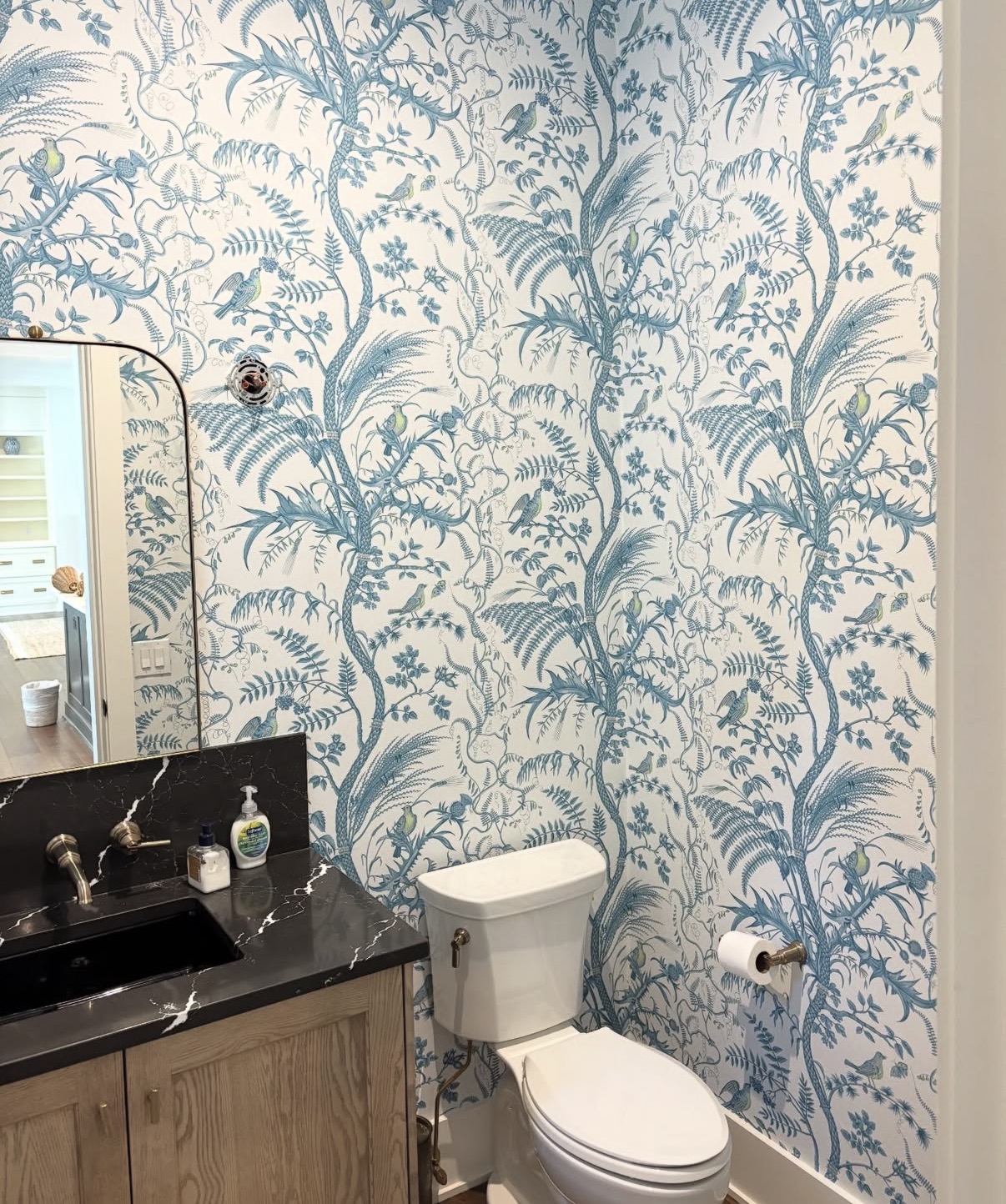Blue fern and songbird toile powder room with black marble vanity and arched mirror