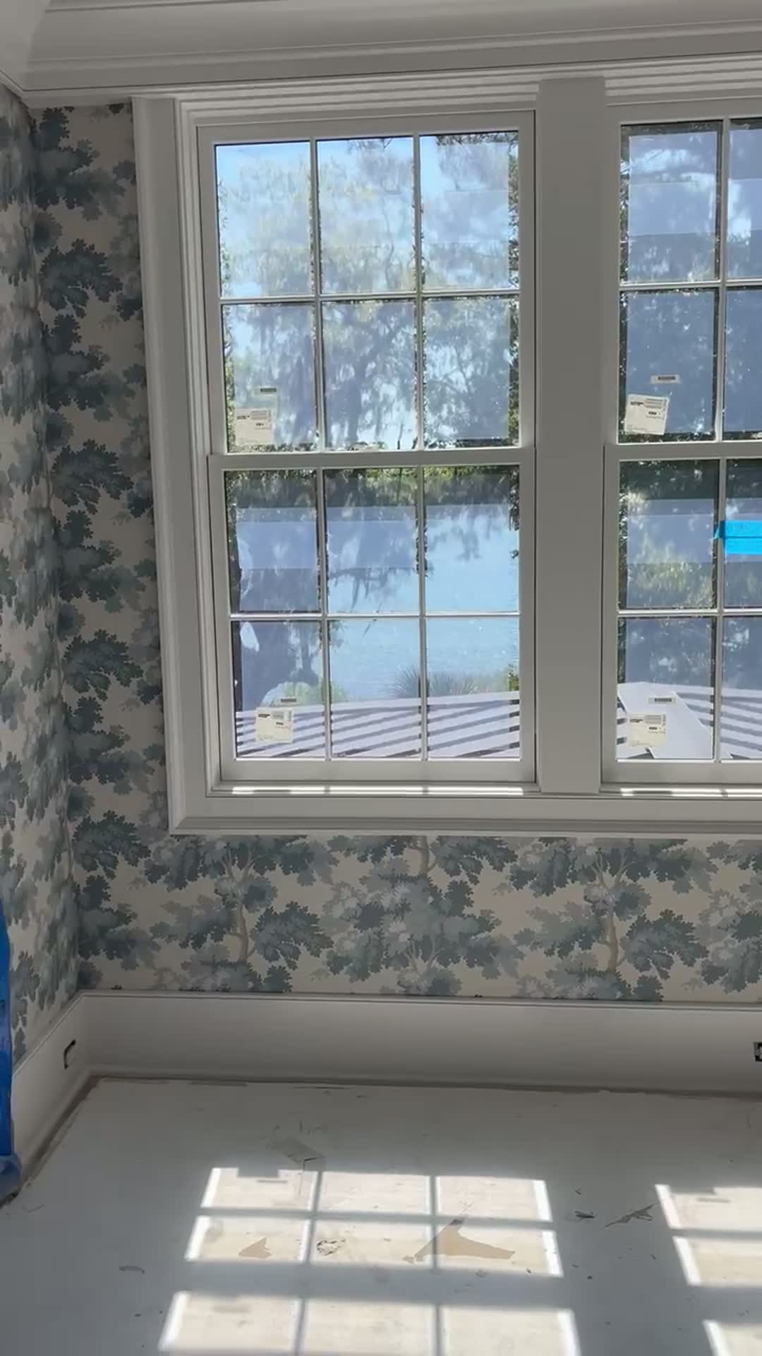 Blue oak-tree wallpaper framing double-hung windows with a Lowcountry water view